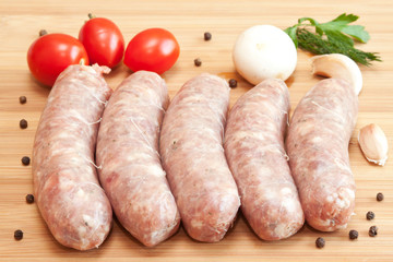 Uncooked sausages with vegetables on the chopping board