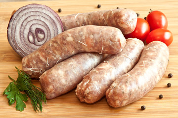 Uncooked sausages with vegetables on the chopping board