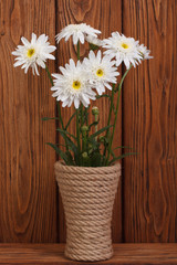 White chrysanthemums in a vase on a  wooden surface