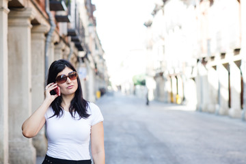 Fototapeta premium Girl with sunglasses waiting and talking to her smartphone