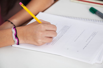 Schoolgirl Writing On Paper At Desk