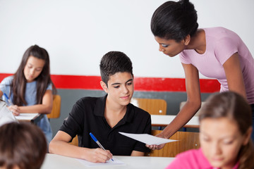 Teacher Showing Paper To Teenage Schoolboy During Examination