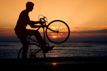 Obraz na płótnie Canvas Riding a bicycle at the sunrise on the beach