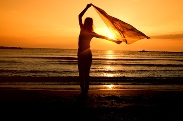 Woman dancing on the beach at sunrise