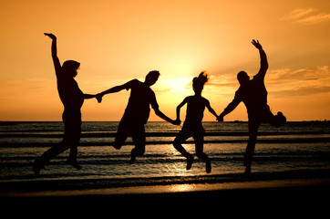 Fototapeta na wymiar Group of happy people parting on the beach at sunrise