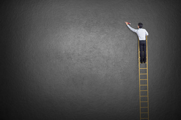 businessman standing on ladder drawing diagrams and graphs