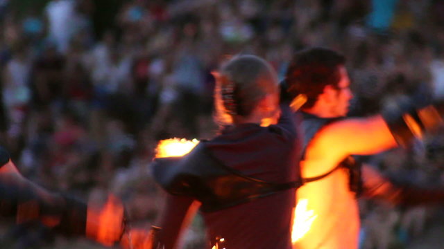 Men and woman dance with burning chain fire pois