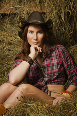 Cowgirl sitting on hay in the stable