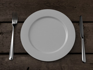 white plate, knife and fork on wooden table