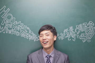 Portrait of young businessman in front of black board with Chinese and English script - obrazy, fototapety, plakaty