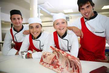 Happy team of young butchers in school kitchen