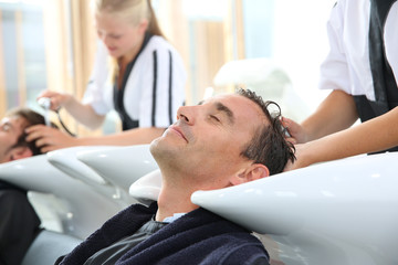 Fototapeta premium Young women in hairdress training washing customer's hair