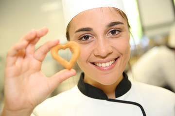Portrait of young pastry cook holding cookie