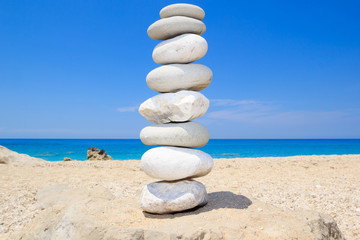 Pebbles stack balance over blue ionian sea in Greece