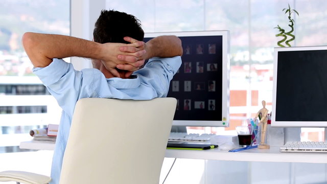 Man relaxing in creative office with hands behind his head