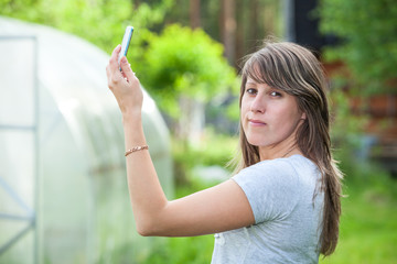 Young woman holding phone up and looking at camera