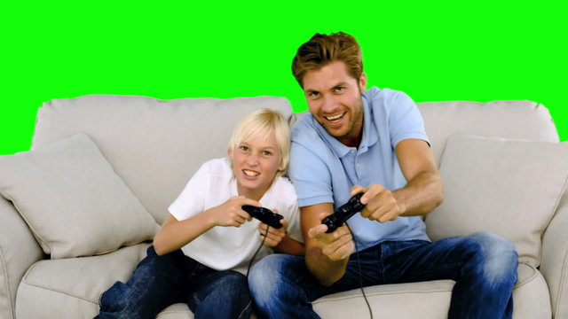 Father and son playing video games on the sofa on green screen