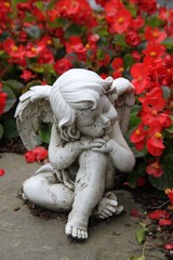 Ruhender Engel zwischen roten Blumen auf einem Grab