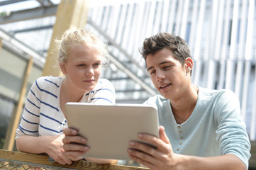Students in school yard using digital tablet
