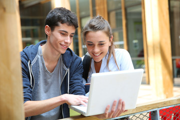 Teenagers working on laptop in school campus