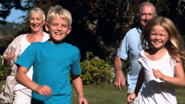 Grandchildren running with their grandparents in a park