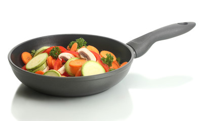 frying pan with vegetables on white