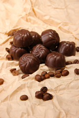 Chocolate candies and coffee beans, on beige paper background