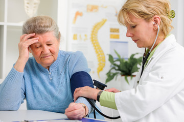 Ärztin misst den Blutdruck und Puls bei Patientin