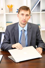 Young businessman with laptop computer shouting down