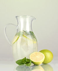 Lemonade in pitcher on green background