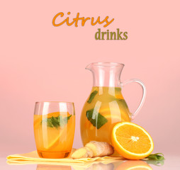 Orange lemonade in pitcher and glass on pink background
