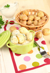 Tender young potatoes with sour cream and herbs in pan