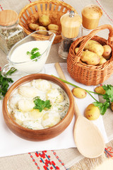 Tender young potatoes with sour cream and herbs in wooden bowl