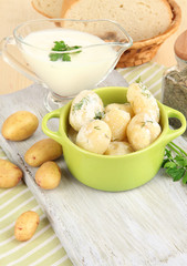 Tender young potatoes with sour cream and herbs in pan