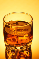 Brandy glass with ice on yellow background