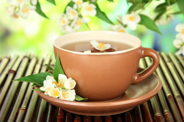 Cup of tea with jasmine, on bamboo mat, on bright background