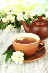 Obraz na płótnie Canvas Cup of tea with jasmine, on wooden table, on bright background
