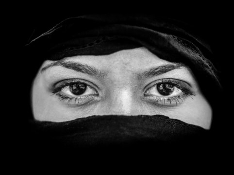 Portrait of beautiful Arab woman wearing black scarf in black an
