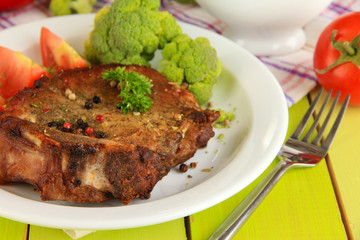 Piece of fried meat on plate on wooden table close-up