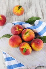 Peaches on board on napkin on table on wooden background © Africa Studio