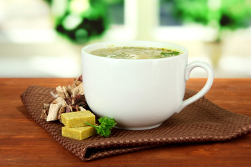 Cup of soup with bouillon cubes on wooden table