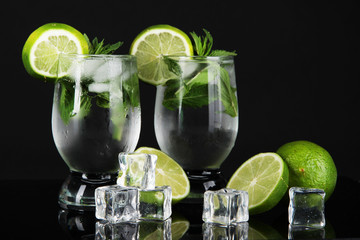 Glasses of cocktail with ice on black background