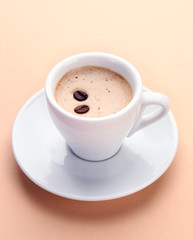 Cup of coffee with coffee beans on beige background