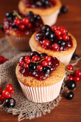 Tasty muffins with berries on wooden table