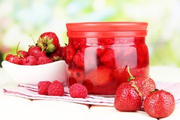 Home made berry jam on wooden table on bright background
