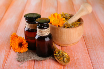 Medicine bottles and calendula flowers on wooden background