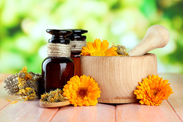 Medicine bottles and calendula flowers on wooden table