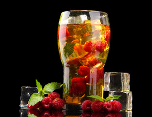 Iced tea with raspberries and mint on black background