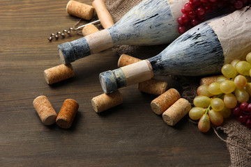 Old bottles of wine, grapes and corks on wooden background