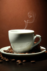 Cup of coffee with smoke on brown background